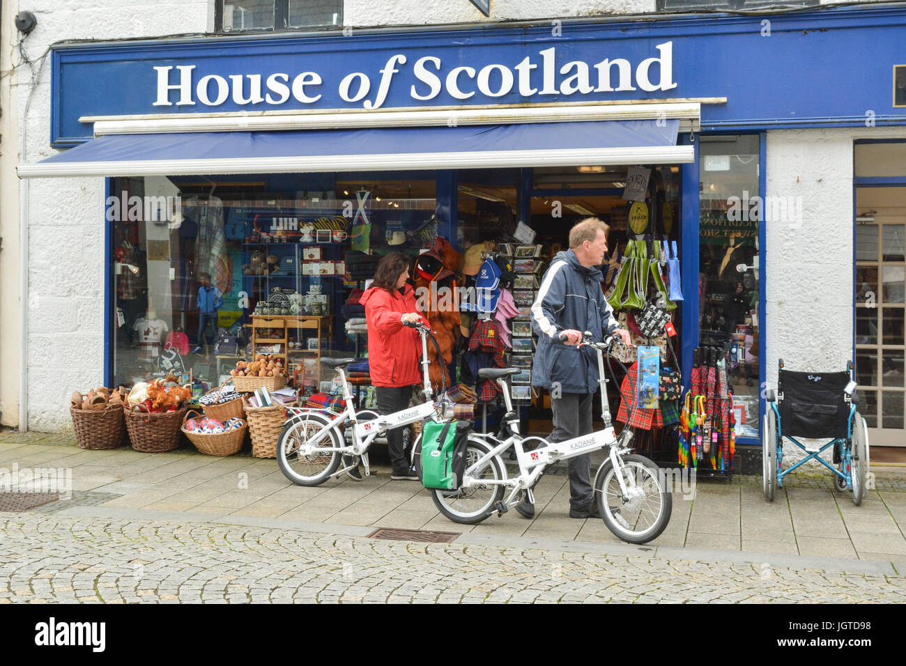 I turisti con ribaltamento elettrico bici al di fuori del negozio di souvenir a Fort William, Scotland, Regno Unito Foto Stock