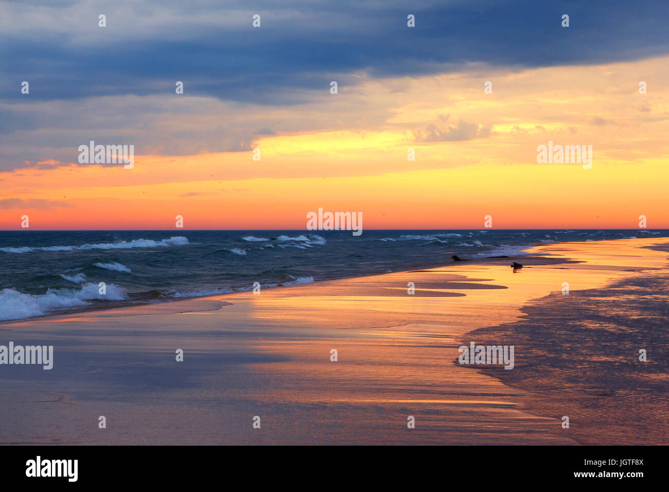 Il lago Michigan tramonto crea riflessi brillanti sulla spiaggia di sabbia. Luce di colori fino alla spiaggia di Ludington parco dello stato Foto Stock