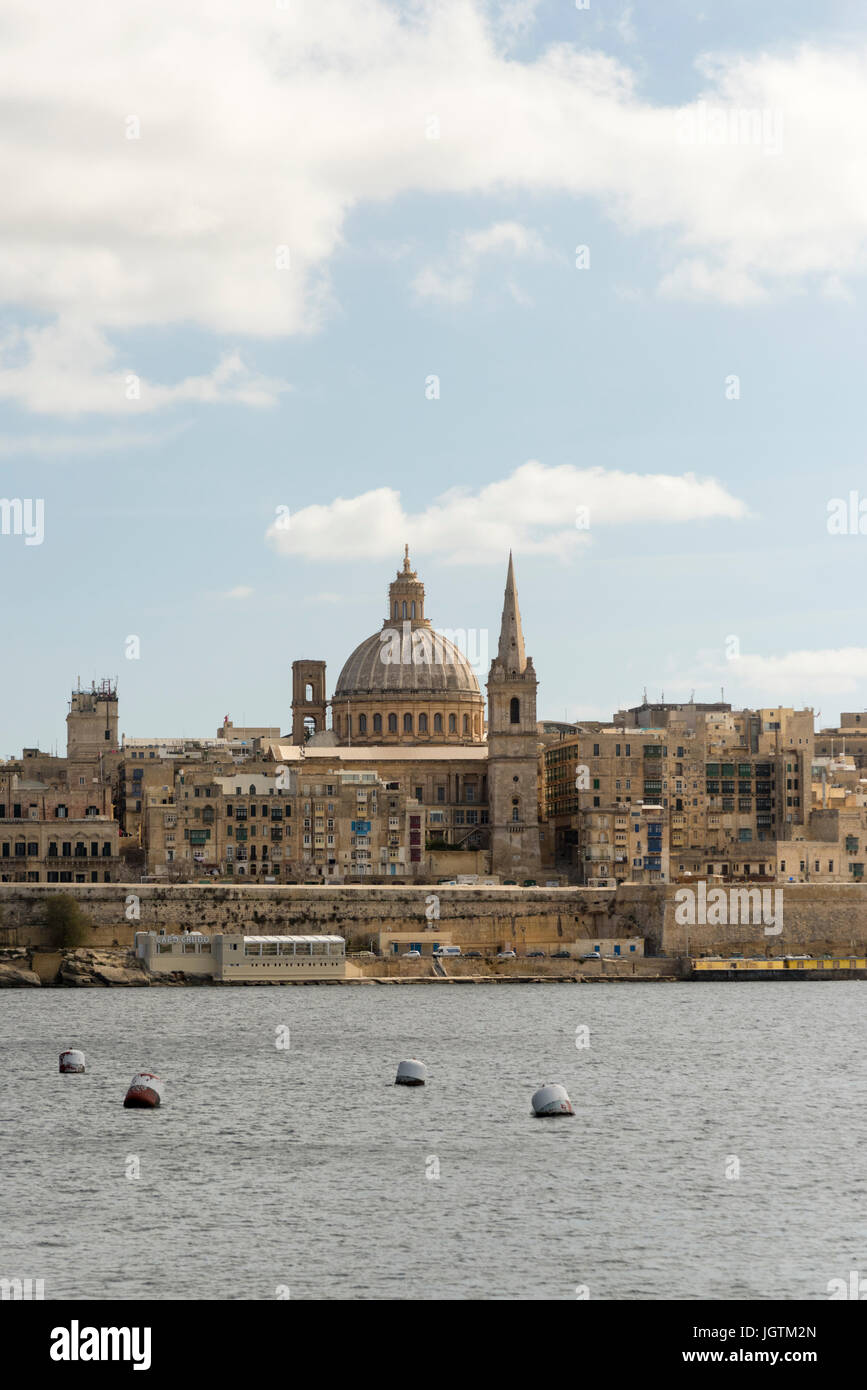Una vista di Valletta, la capitale di Malta attraverso il porto da Sliema che mostra la chiesa carmelitana la cupola e la torre Foto Stock