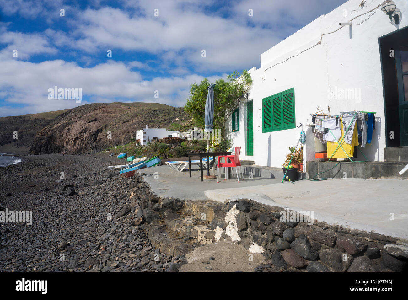 Piccola casa di pescatori con i panni appesi, la spiaggia del villaggio di pescatori Playa Quemada, Lanzarote, Isole canarie, Spagna, Europa Foto Stock