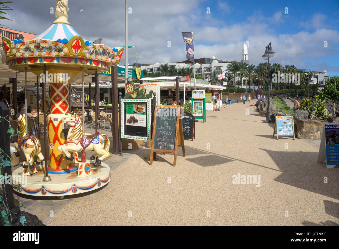 I bambini di merry-go-round e negozi presso il lungomare di Playa Dorada Beach, Playa Blanca, Lanzarote, Isole canarie, Spagna, Europa Foto Stock