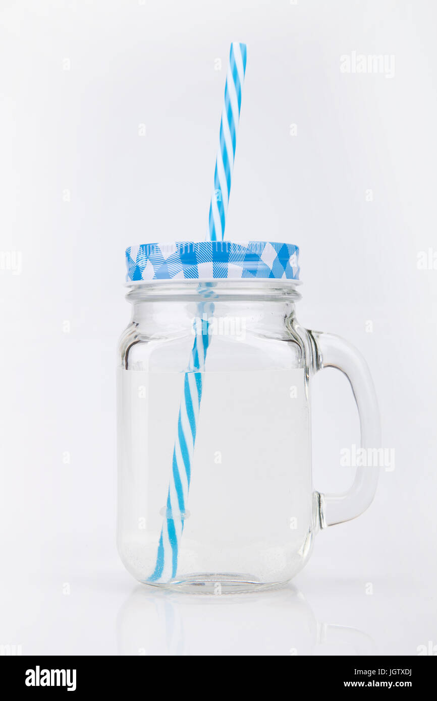 Vetro blu Mason jar lo sbarramento rotante su una superficie bianca. Tumbler isolati su sfondo bianco. Foto Stock