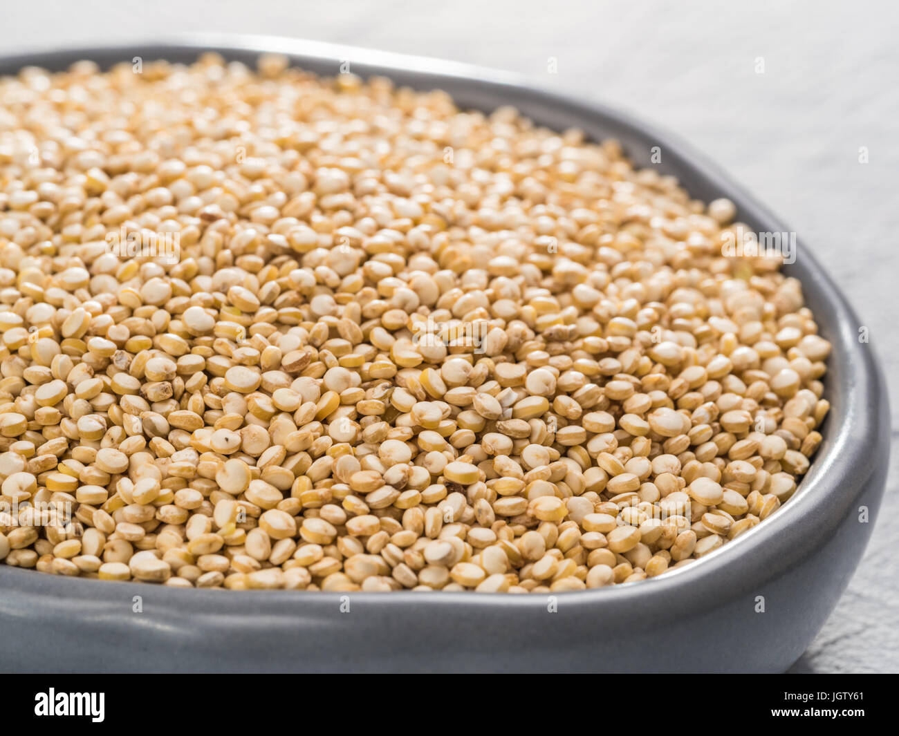 Vista ravvicinata sul secco di quinoa in piastra sul cemento grigio sfondo Foto Stock