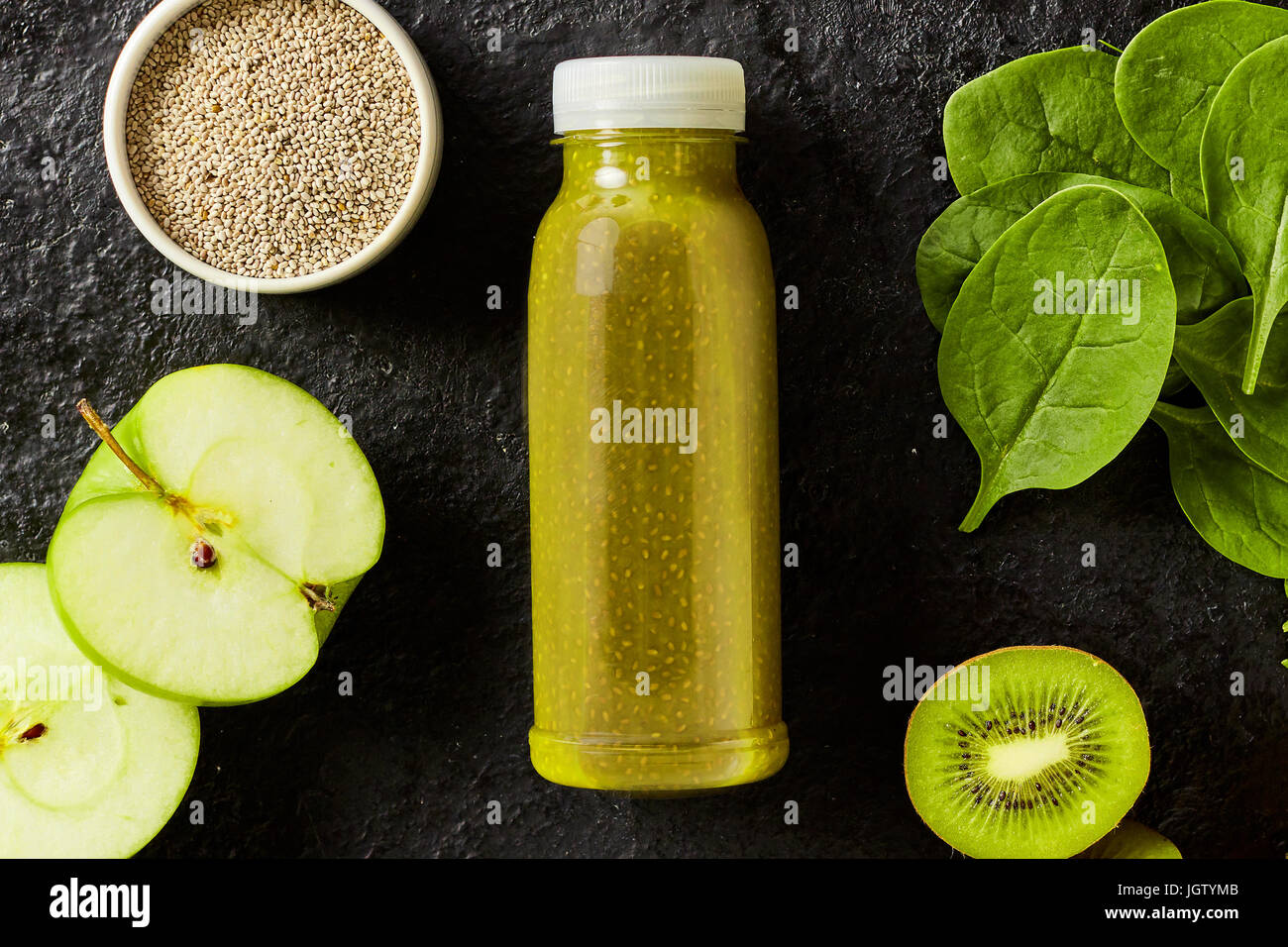 Spinaci freschi, kiwi e apple smoothie con semi di chia per una colazione energizzante con gli ingredienti che circonda una bottiglia di bevanda miscelata Foto Stock