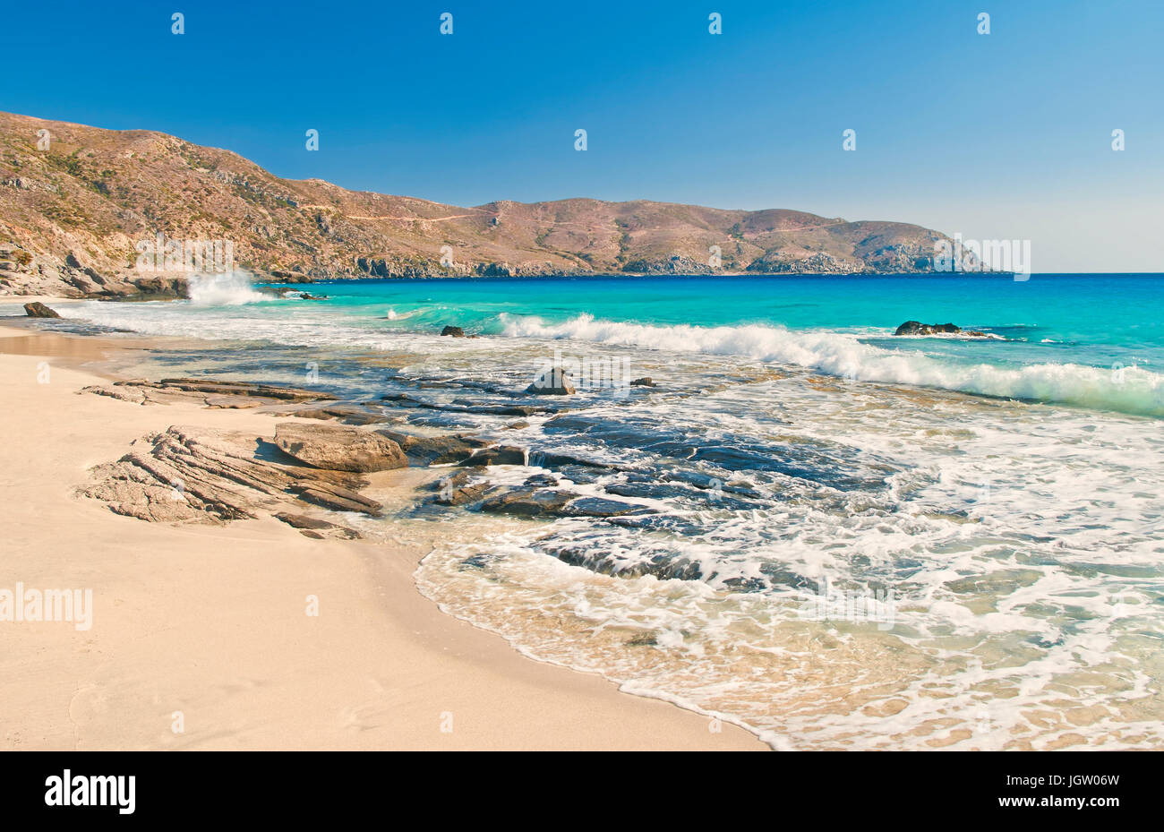 Spiaggia selvaggia con rocce e mare dolce surf del mare Mediterraneo con le montagne a sfondo su soleggiate giornate estive, Kedrodasos, Creta Foto Stock