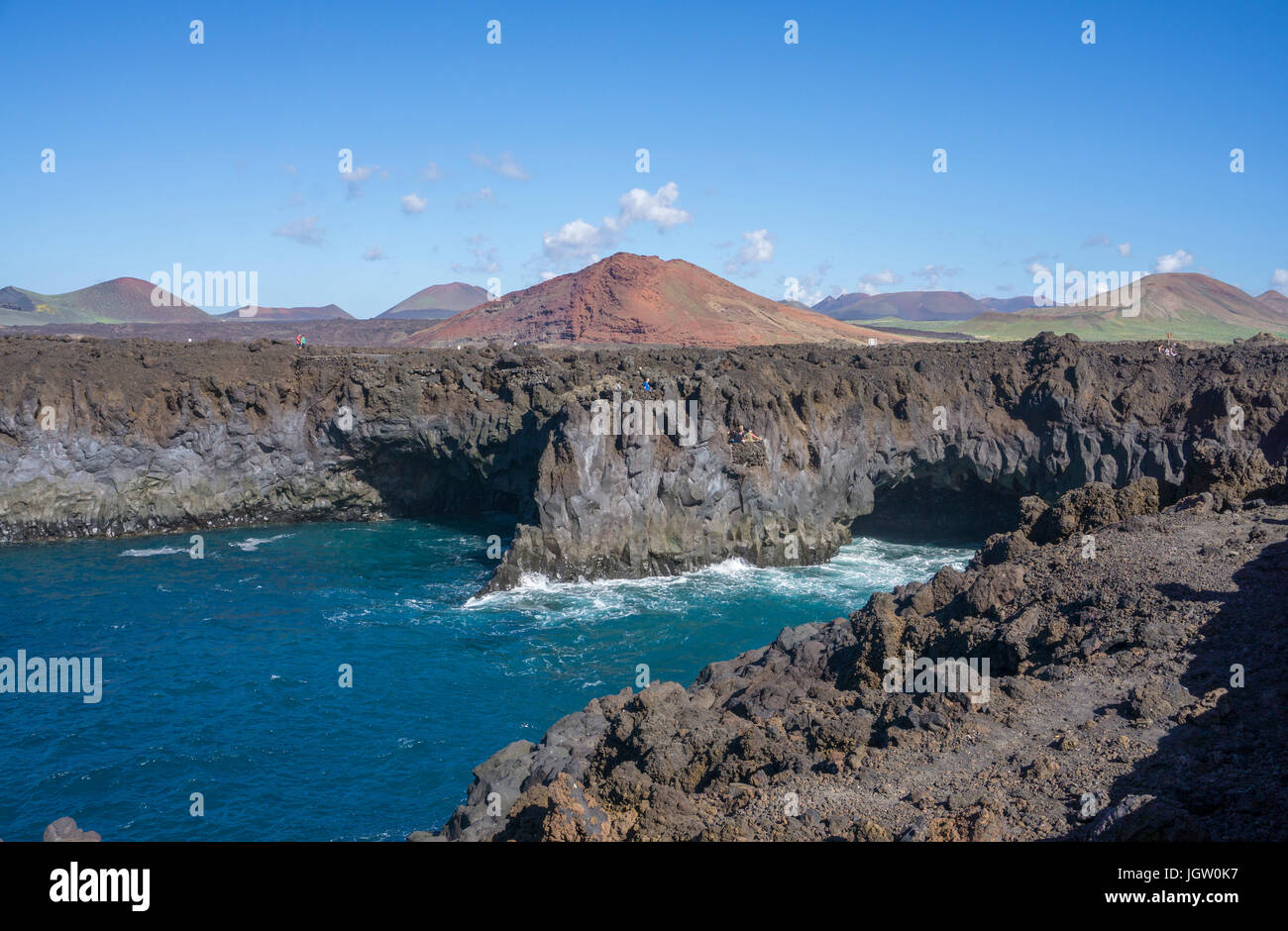 Rocciosa costa vulcanica a Los Hervideros, dietro il fuoco montagne Montanas del Fuego, El Golfo, Lanzarote, Isole canarie, Spagna, Europa Foto Stock