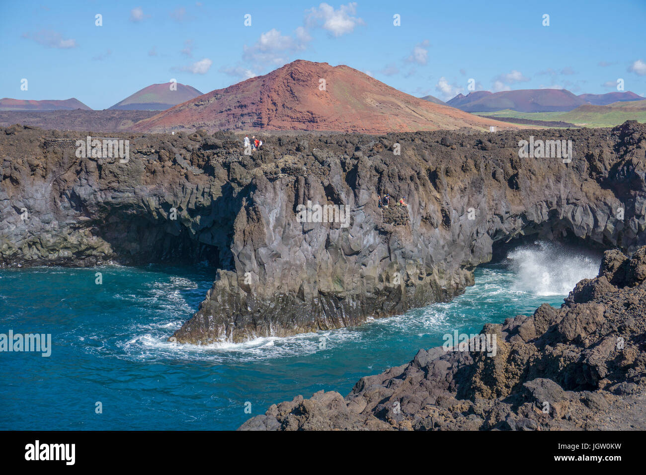 Rocciosa costa vulcanica a Los Hervideros, dietro il fuoco montagne Montanas del Fuego, El Golfo, Lanzarote, Isole canarie, Spagna, Europa Foto Stock