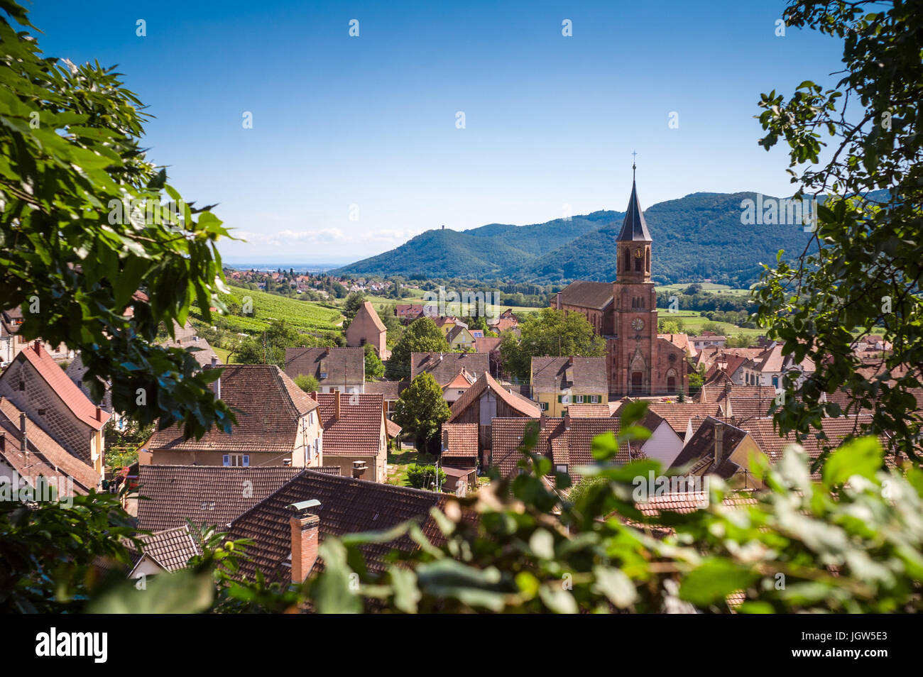 Vista panoramica del tipico villaggio alsaziano Wihr-au-Val con tetti, chiesa e colline in background Foto Stock