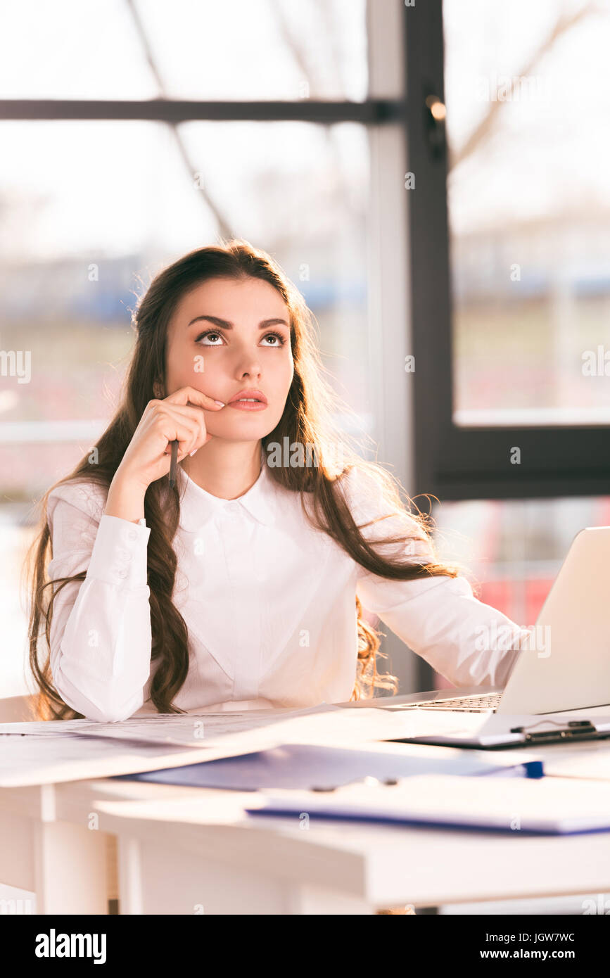 Riflessivo imprenditrice seduti al posto di lavoro con il computer portatile in ufficio moderno Foto Stock