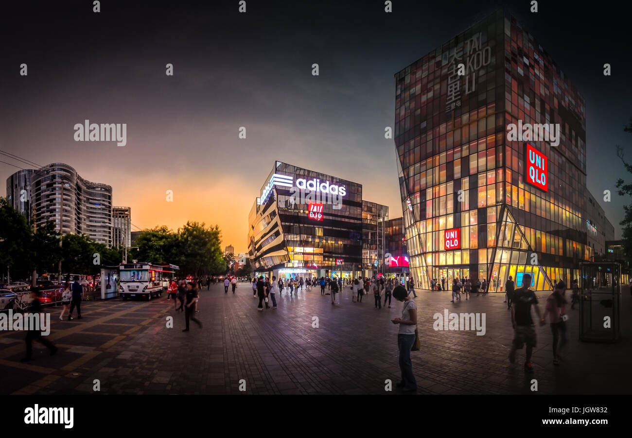 La piazza dello shopping di fronte Uniqlo edificio pieno di gente in Sanlitun Beijing durante il tramonto dopo un temporale Foto Stock