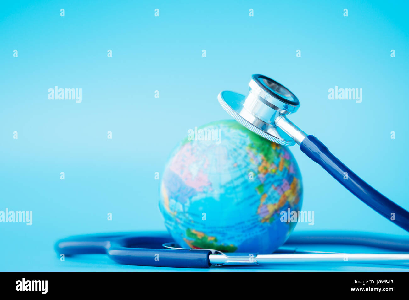 Terra verde giorno, salvare la wold e Global Healthcare concetto. Uno stetoscopio avvolto intorno al globo su sfondo blu. Foto Stock