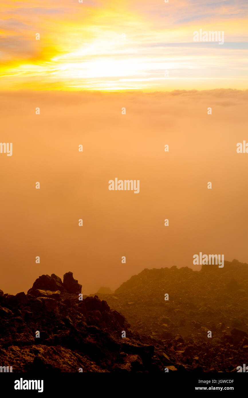 Il sorgere del sole dietro le nuvole sulla cima di Haleakala a Maui, Hawaii, Stati Uniti d'America. Foto Stock