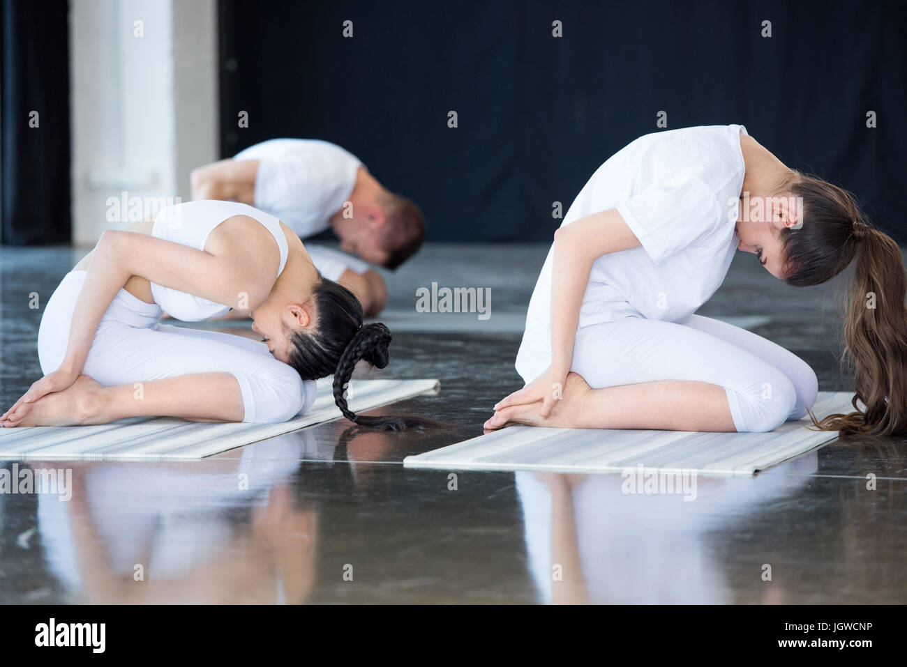 Le donne a praticare lo yoga nel bambino pongono (Balasana) con istruttore presso la palestra Foto Stock