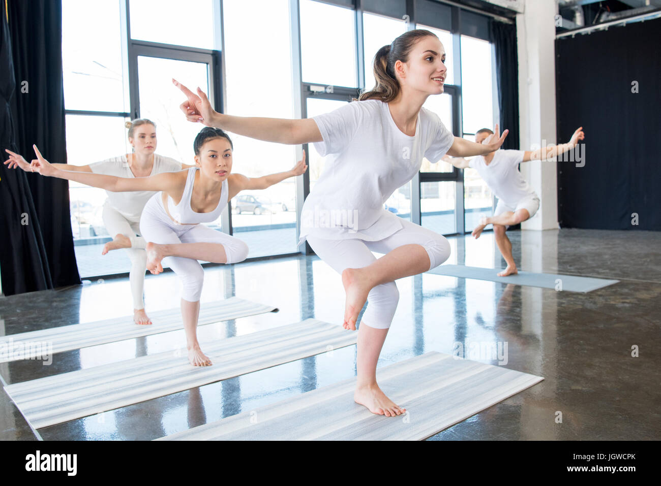 Le ragazze facendo Gallo d'Oro sorge su una gamba sola posizione yoga con istruttore in ambienti interni Foto Stock