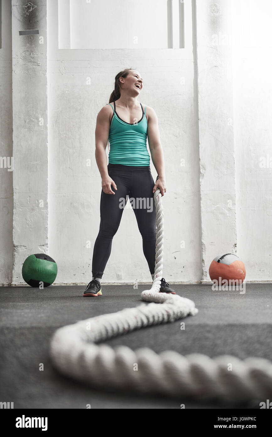 Donna che mantiene la battaglia di corda in croce palestra di formazione Foto Stock