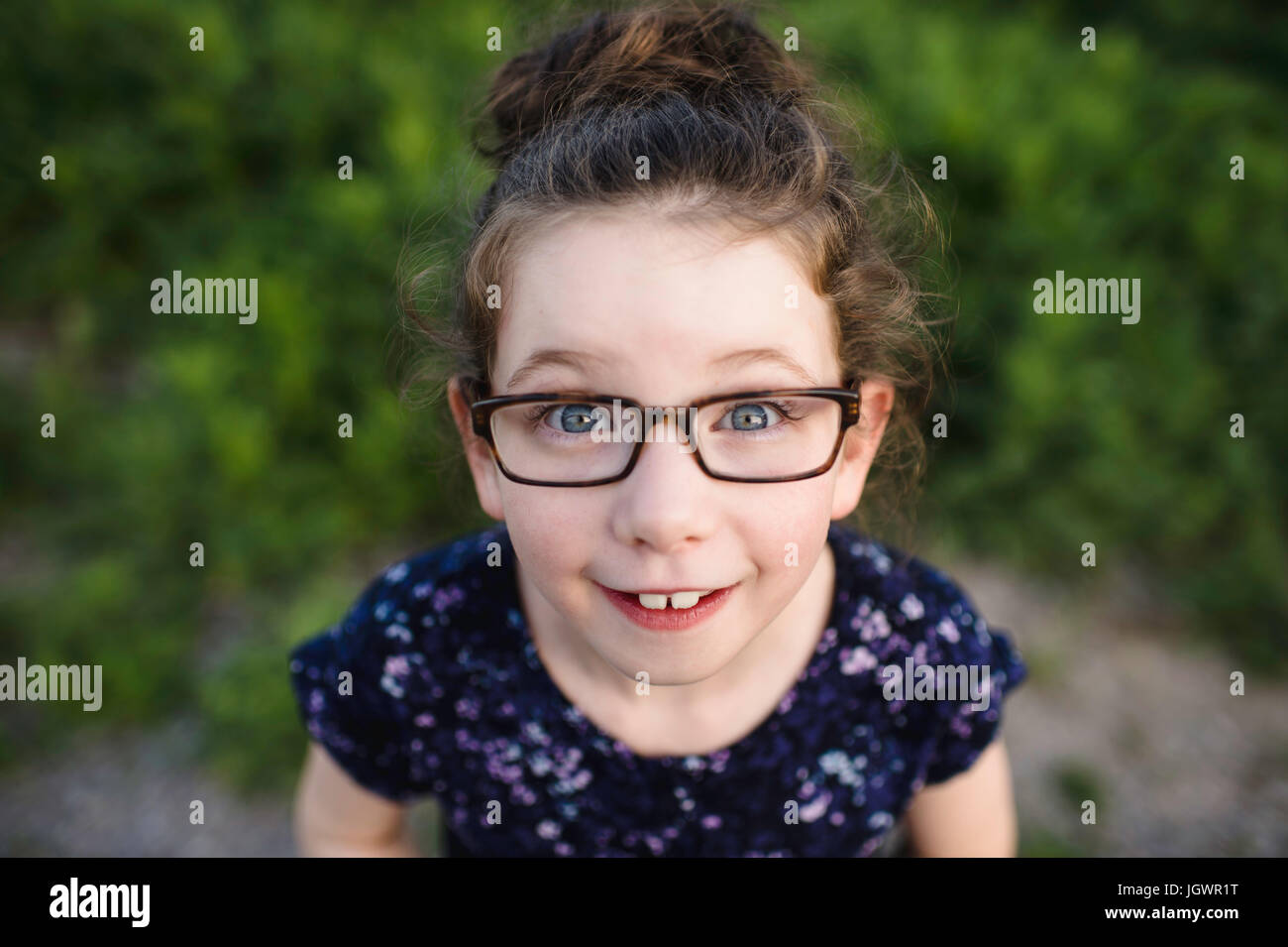 Ritratto di ragazza carina indossando occhiali cercando fino alla fotocamera Foto Stock