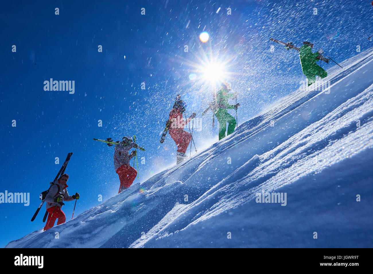 Cinque sciatori maschio trascinarsi faticosamente fino ripido versante soleggiato, Aspen, Colorado, STATI UNITI D'AMERICA Foto Stock