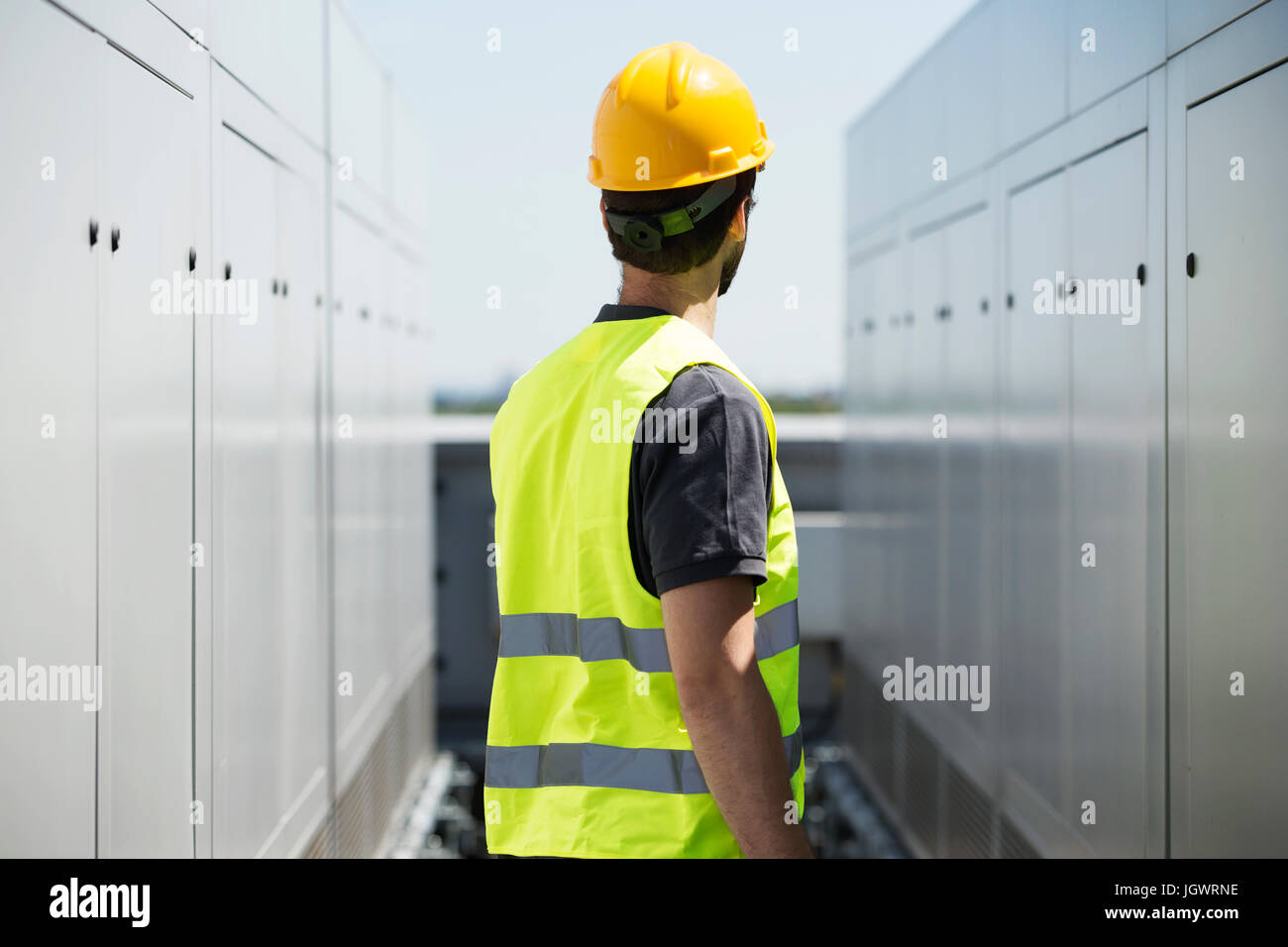 Operaio edile, indossare un elmetto e hi vis vest, all'aperto, vista posteriore Foto Stock