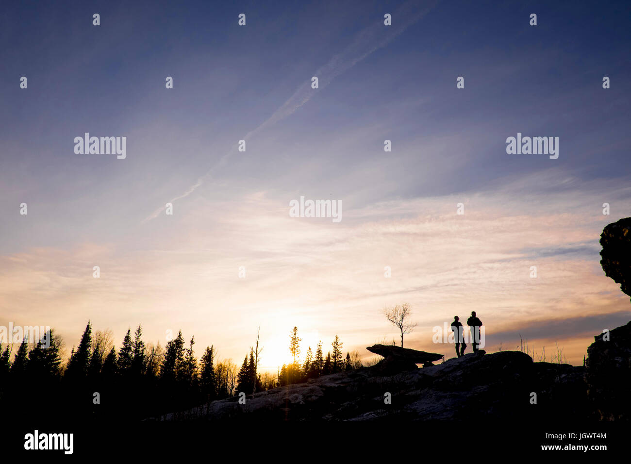 Silhouette di amici sulla parte superiore delle rocce al tramonto, Bolshoy Ural, Sverdlovsk, Russia, Europa Foto Stock