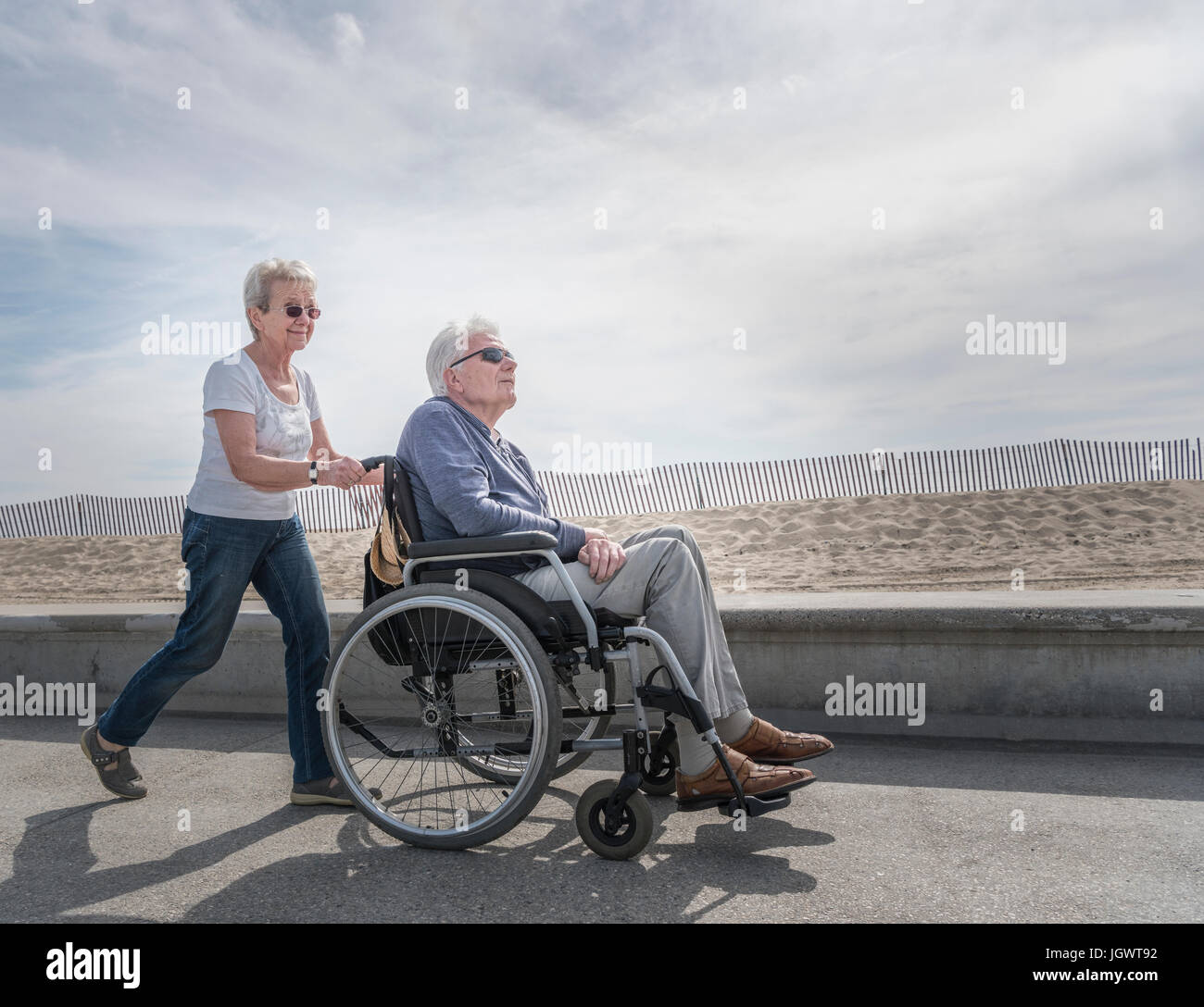 Senior donna spingendo il marito in carrozzella a beach, Santa Monica, California, Stati Uniti d'America Foto Stock