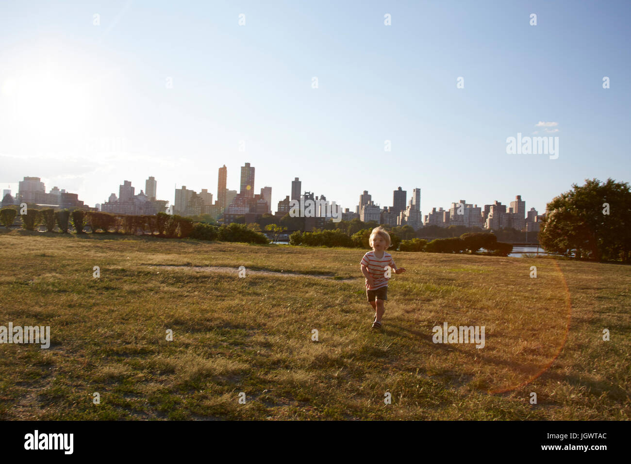 Ragazzo in esecuzione nel parco di fronte skyline di New York, Stati Uniti d'America Foto Stock