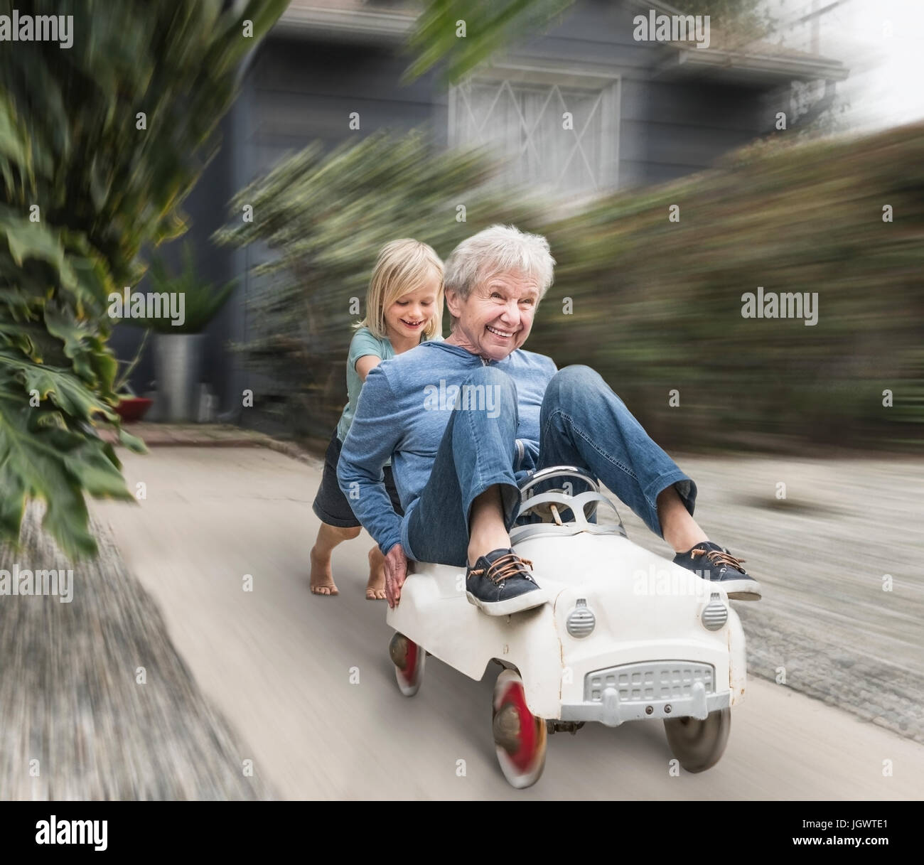 Nipote spingendo la nonna sul suo giocattolo auto Foto Stock