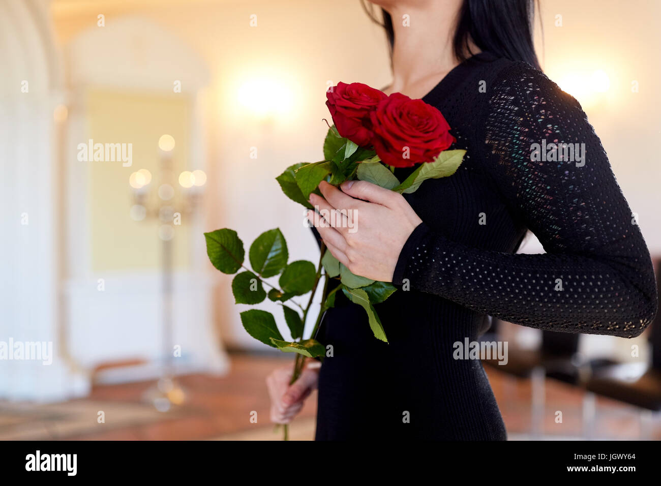 Donna con rose rosse al funerale nella chiesa Foto Stock