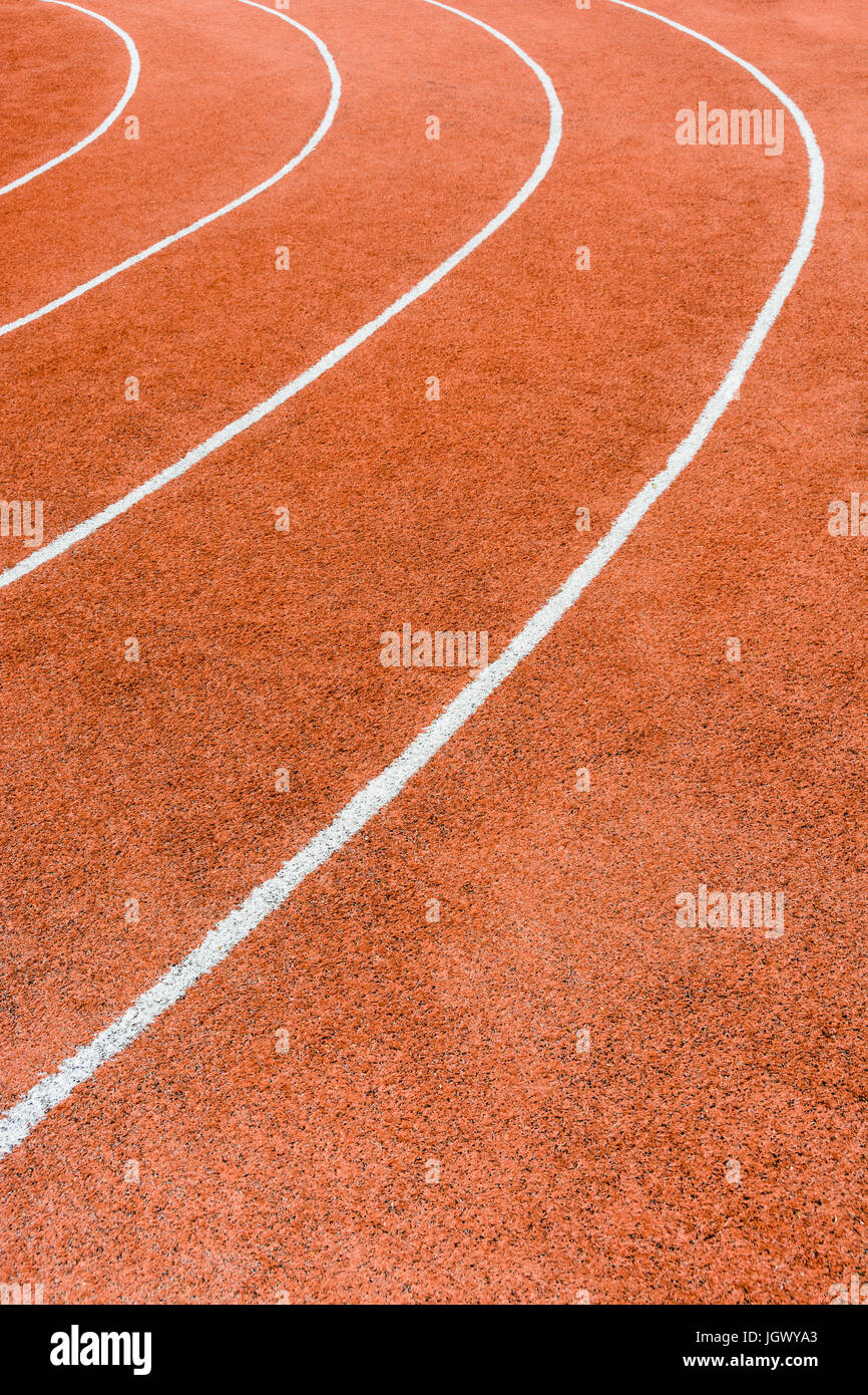 Vista ravvicinata di una pista atletica rossa con linee bianche che delimitano le corsie. Foto Stock
