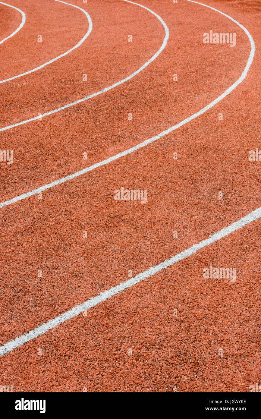 Vista ravvicinata di una pista atletica rossa con linee bianche che delimitano le corsie. Foto Stock