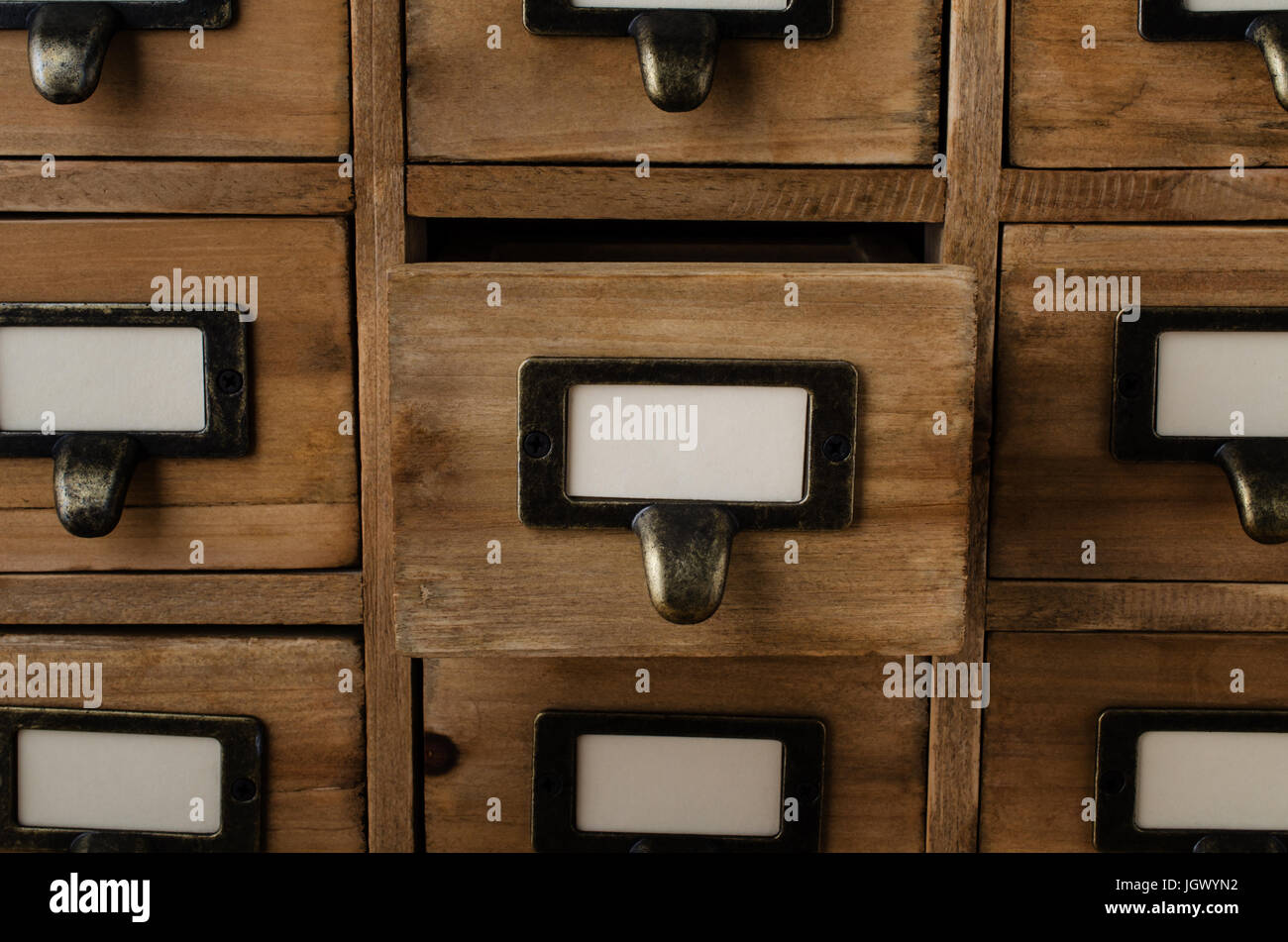 Un vecchio stile armadio in legno della biblioteca indice scheda cassetti con Portaetichette ed etichette vuote rivolta verso il lato anteriore. Un cassetto di mezzo è aperto. Foto Stock