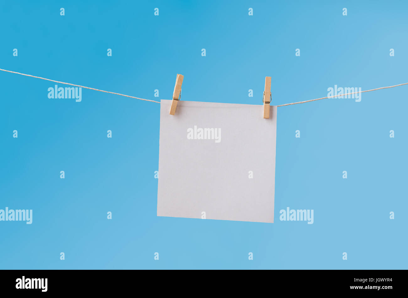 Singola, quadrato bianco della carta bianca, sospesa da una linea di lavaggio mediante due pioli di legno. Lasciato vuoto per fornire spazio copia. Foto Stock