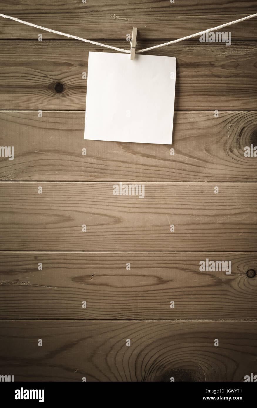 Una singola piazza della nota carta, ancorato a una stringa linea di lavaggio con asse di legno recinzione in background. Bassa saturazione e vignette dà un re Foto Stock