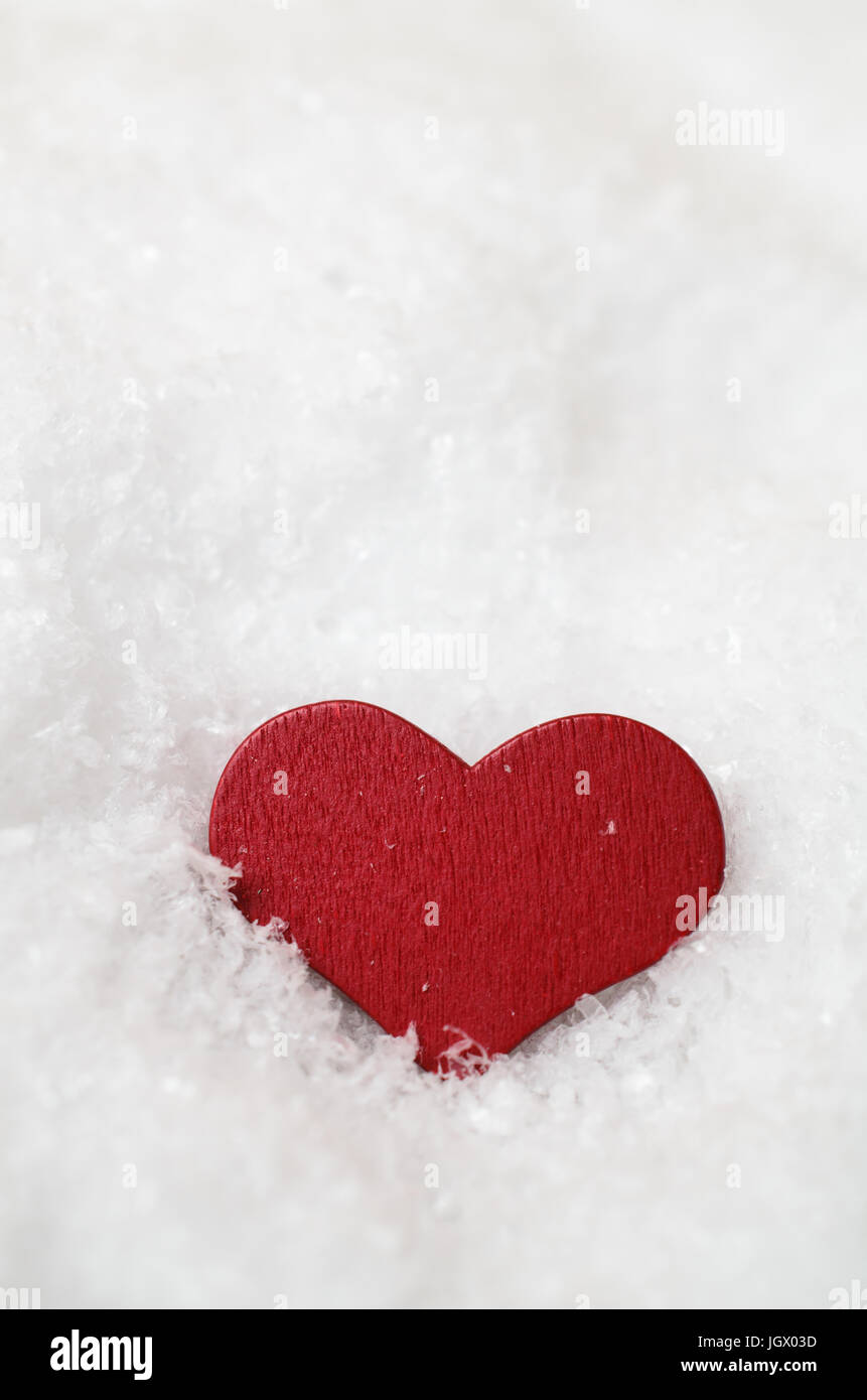 Un rosso, cuore di legno, si stabilirono in posizione eretta nella neve caduti (artificiale), e che è rivolta in avanti appena al di sotto del livello dell'occhio. Copia spazio sopra. Foto Stock