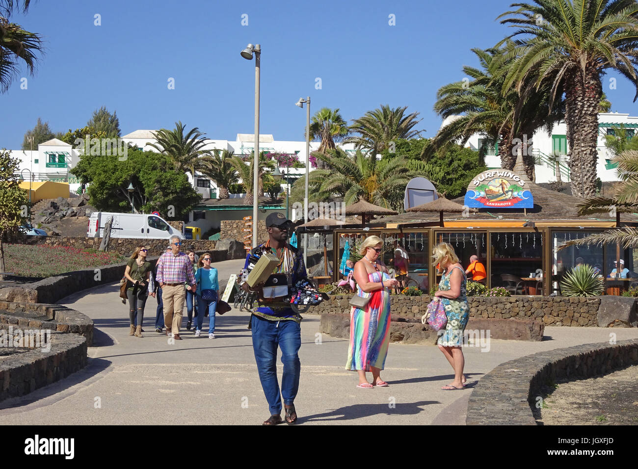 Afrikanischer strassenhaendler verkauft armbanduhren an der promenade beim badestrand playa de Las Cucharas, costa teguise, Lanzarote, kanarische inse Foto Stock