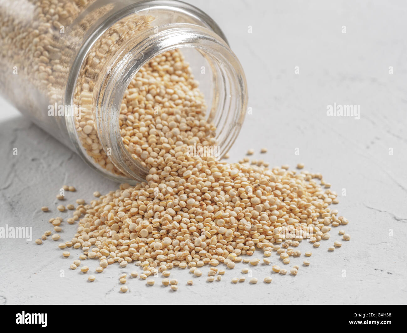 Grano di quinoa. Non cotti materie quinoa in banca su sfondo grigio. Sano cibo vegan concetto e pattern. Foto Stock