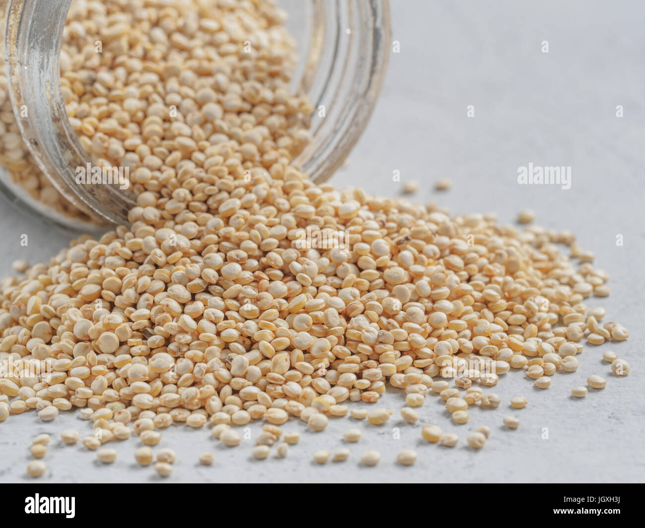 Grano di quinoa. Non cotti materie quinoa in banca su sfondo grigio. Sano cibo vegan concetto e pattern. Foto Stock