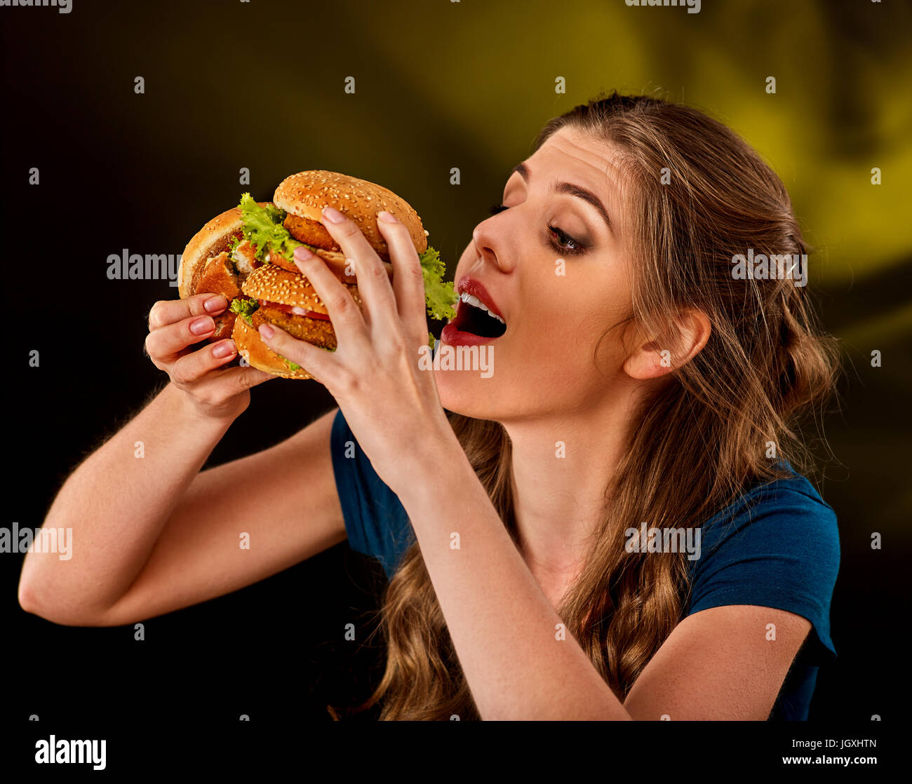 Donna di mangiare hamburger. Studente consumano il fast food sulla tabella. Foto Stock
