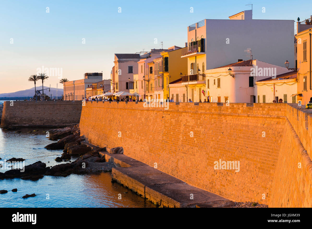 Alghero città vecchia skyline, una vista di Alghero al tramonto con il grande mare medievale parete - dei Bastioni Marco Polo - in primo piano, SARDEGNA. Foto Stock