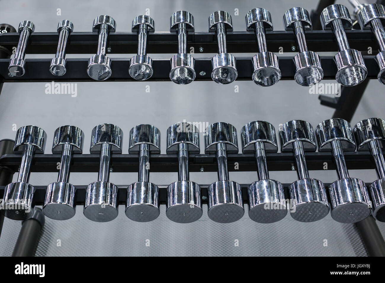 Righe di metallo manubri su rack in palestra o sport club. Peso attrezzatura di formazione. Foto Stock