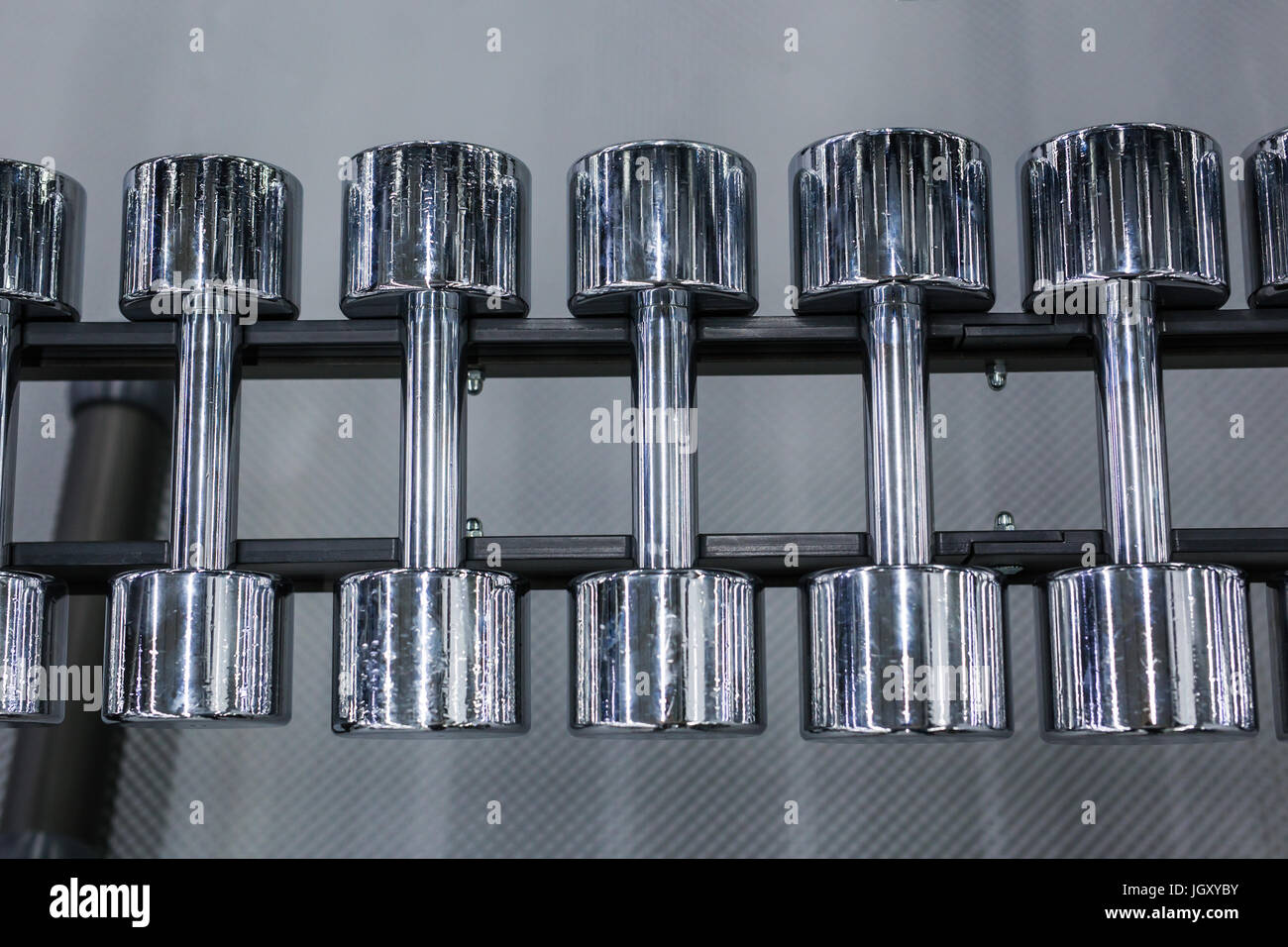 Righe di metallo manubri su rack in palestra o sport club. Peso attrezzatura di formazione. Foto Stock