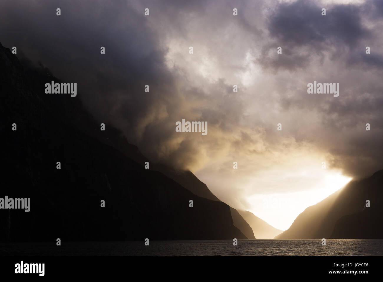 Sole brillante di flussi di luce attraverso inquietanti nubi come appendere sopra le maestose cime innevate, illuminazione di un percorso a più livelli attraverso le montagne. Foto Stock