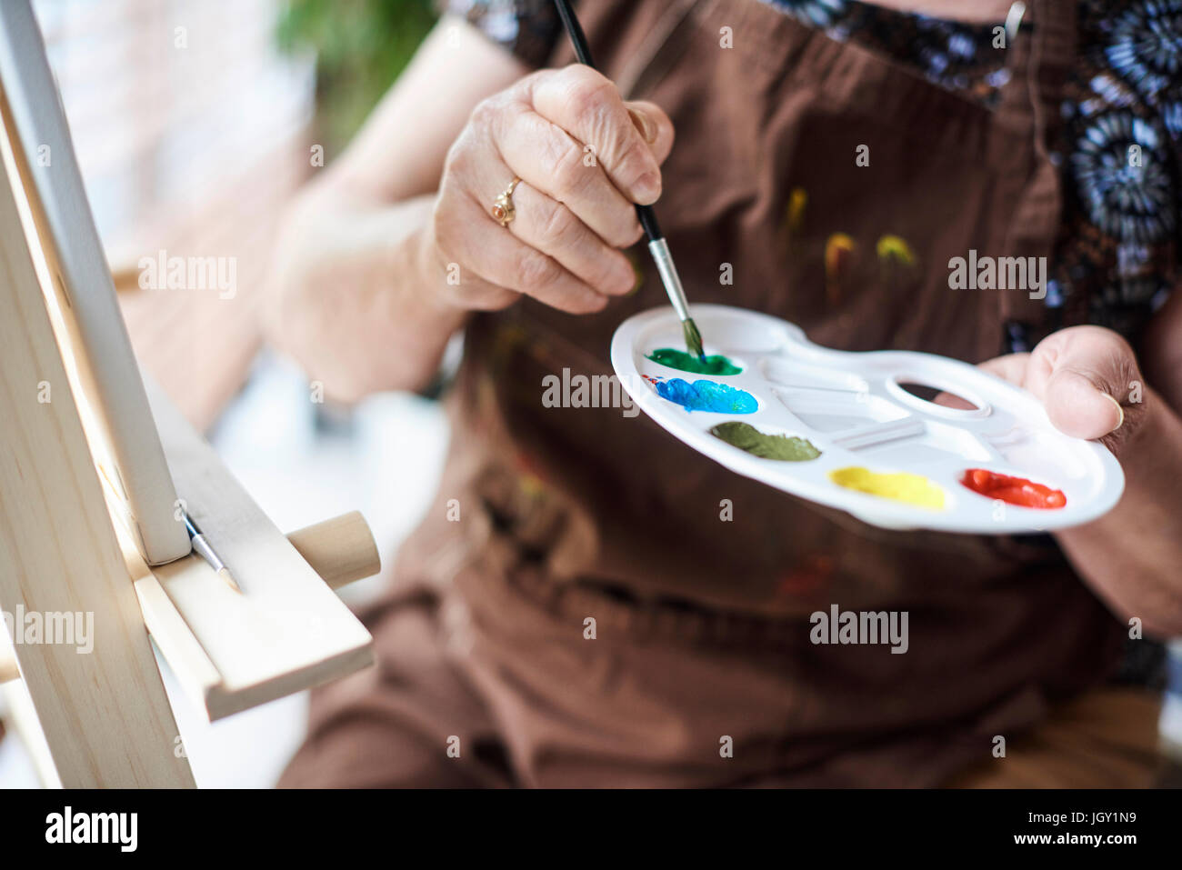 Donna che mantiene tavolozza con pennello e vernici Foto Stock