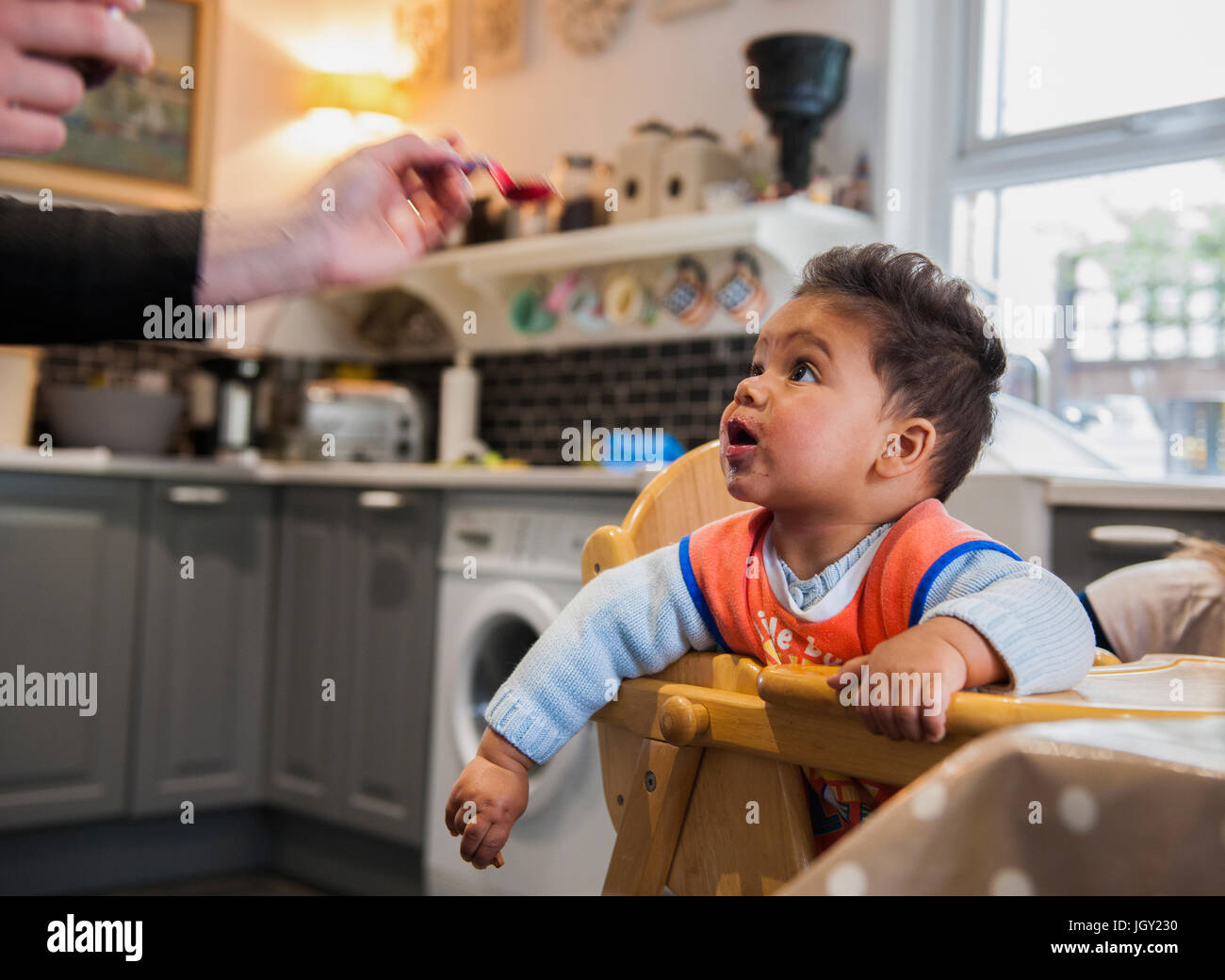 Baby boy nel seggiolone essendo alimentato Foto Stock