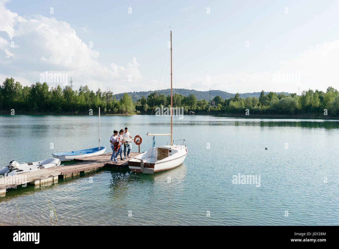 Amici in piedi sul molo, imbarco in barca a vela Foto Stock
