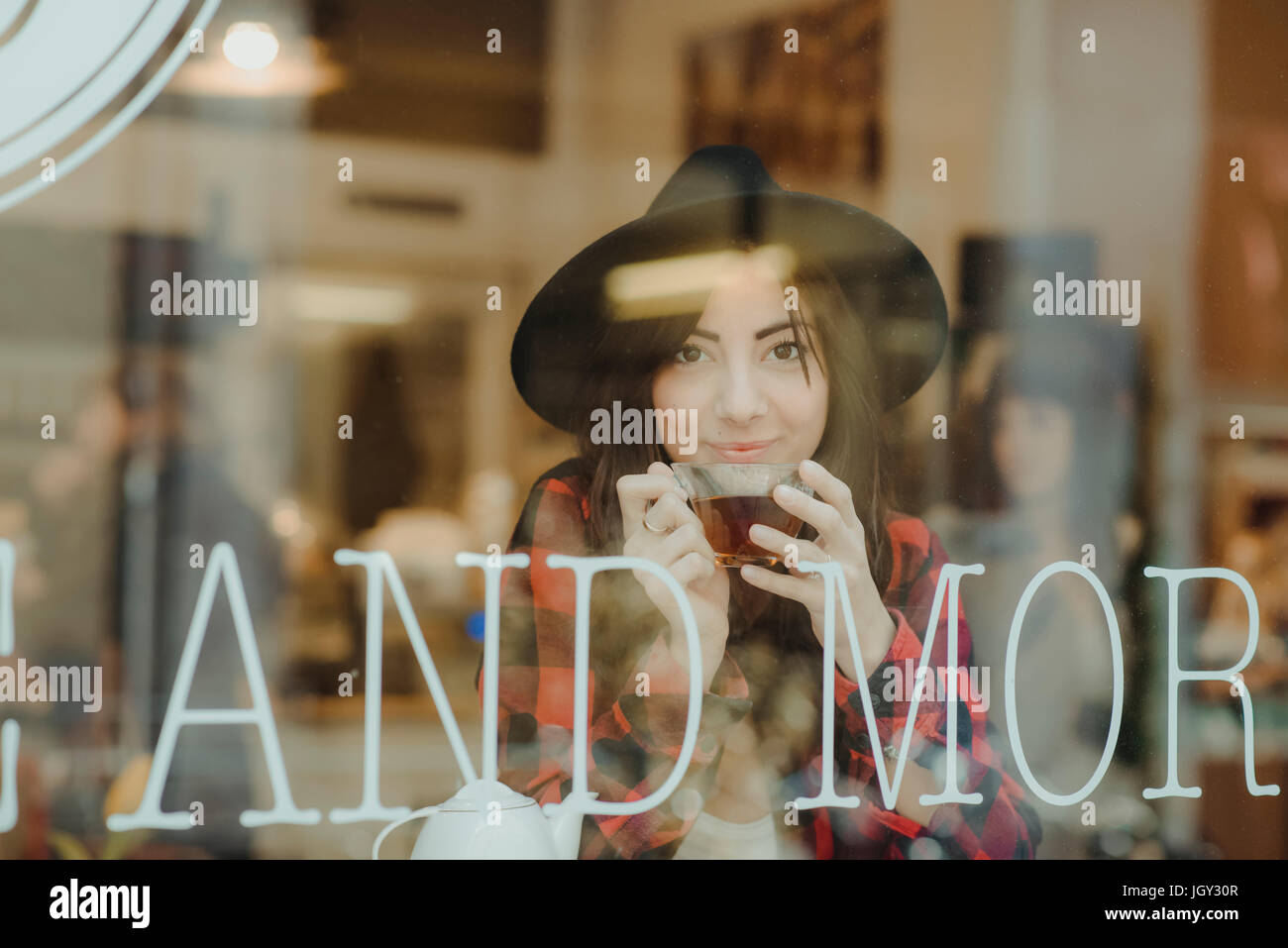Ritratto di giovane donna seduta al cafe, vista attraverso la finestra Foto Stock