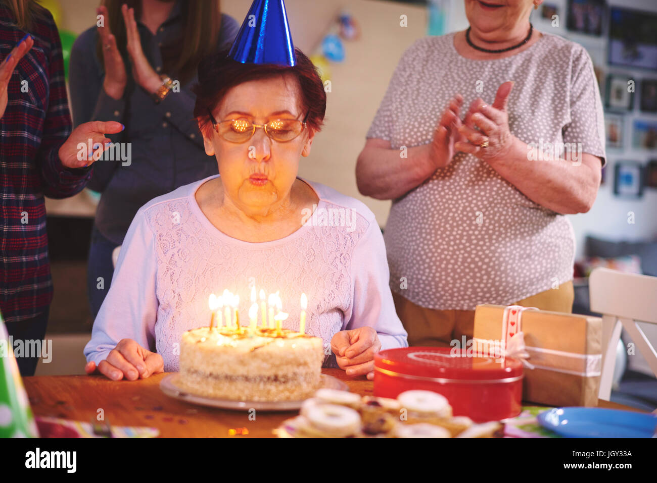 Senior donna soffiando le candeline sulla torta di compleanno a parte Foto Stock