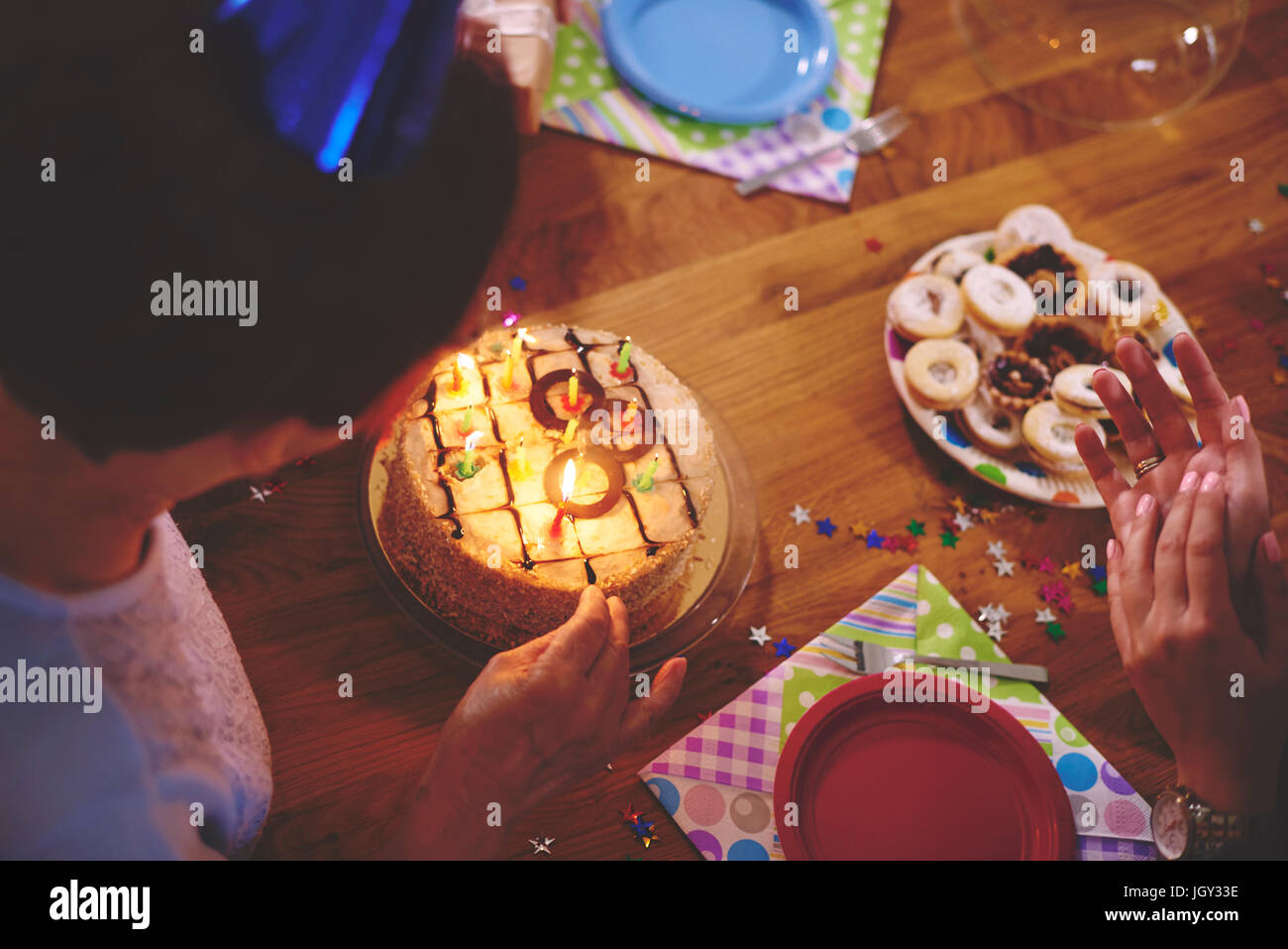 Senior donna che guarda la torta di compleanno a parte Foto Stock