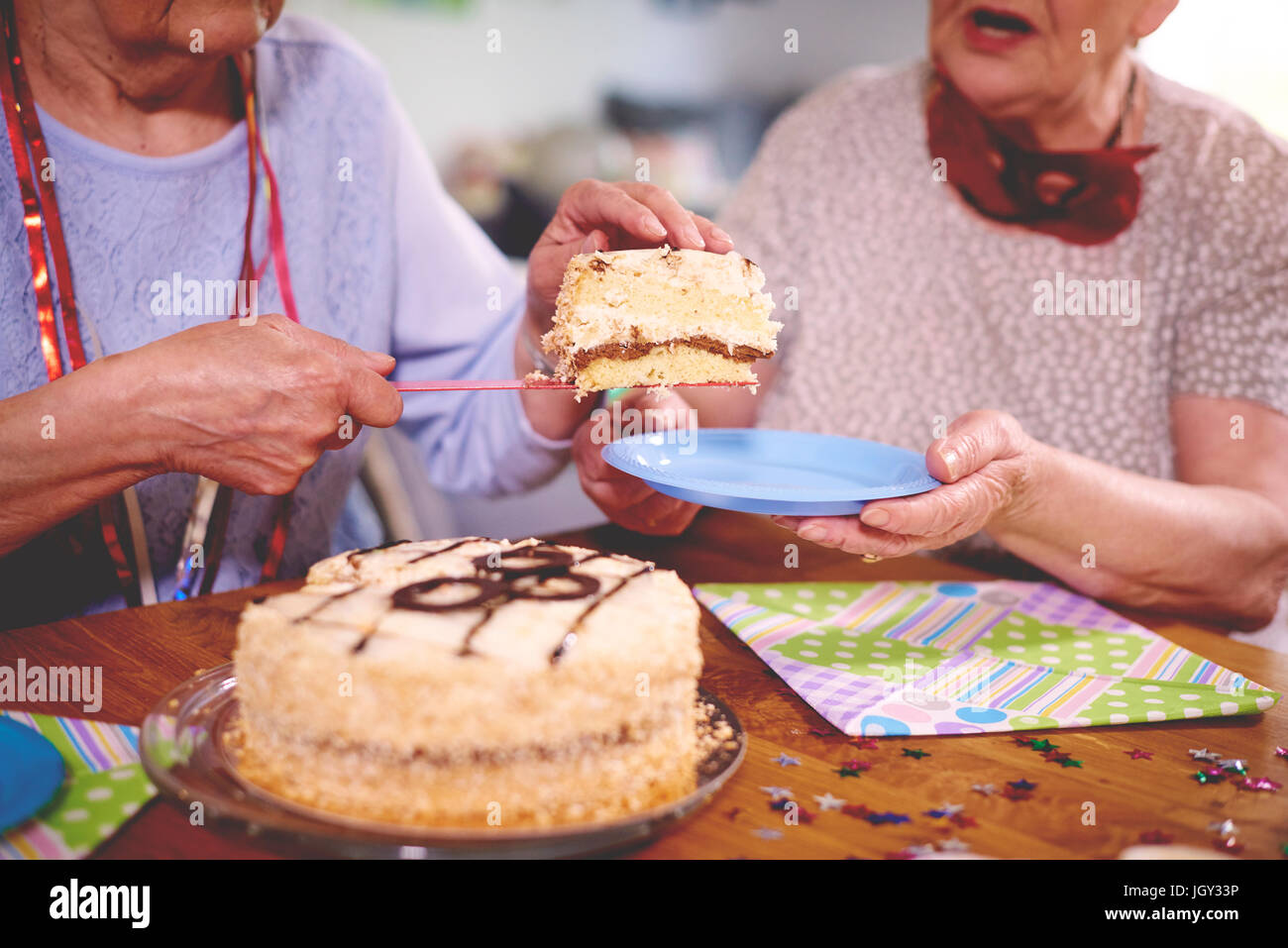 Le donne anziane di servire la torta di compleanno a parte Foto Stock