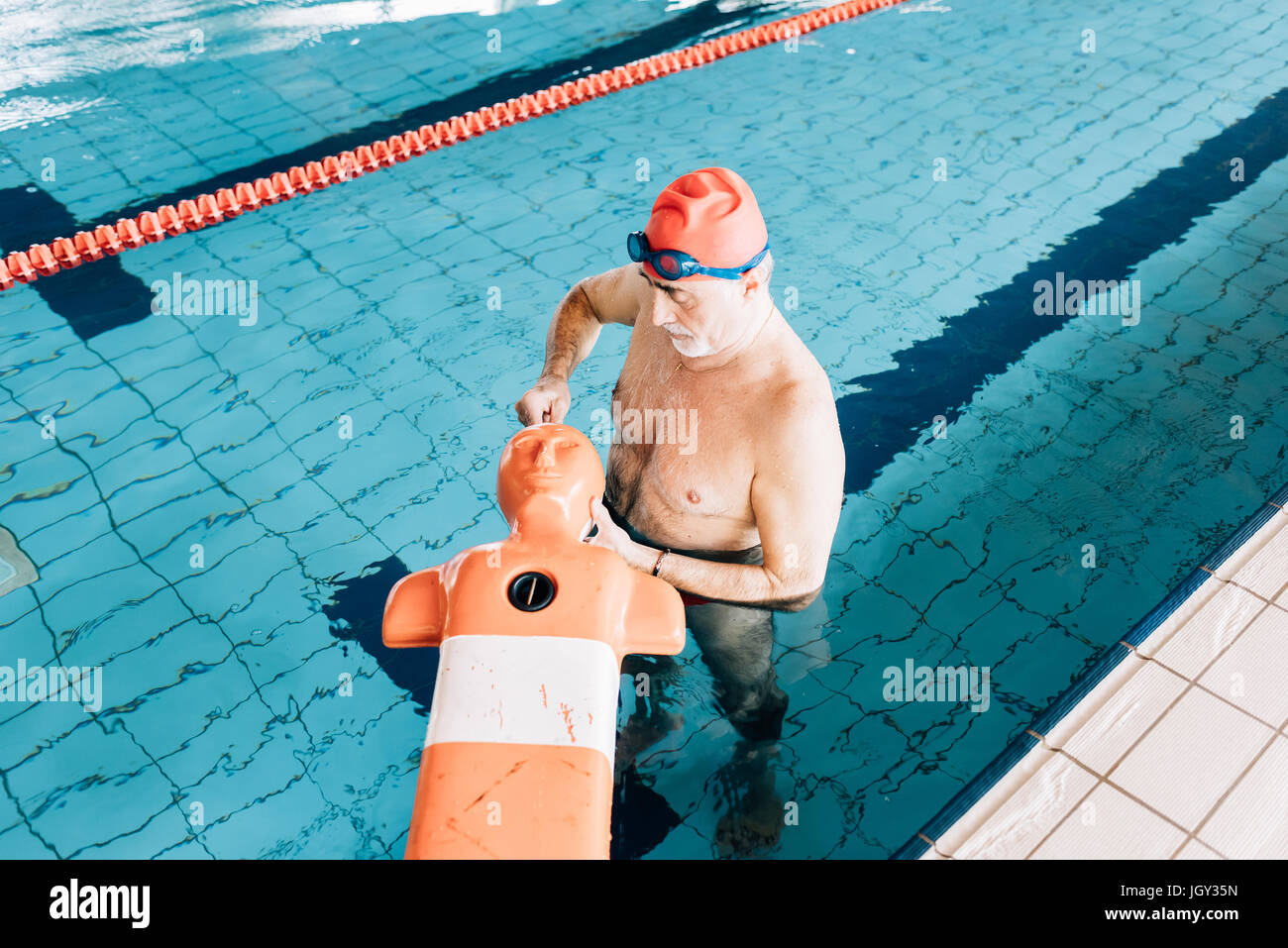 Senior uomo preparare lifesaving attrezzature di formazione in piscina Foto Stock