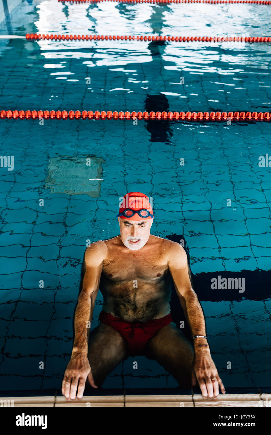 Senior uomo rilassante in acqua dal bordo della piscina Foto Stock